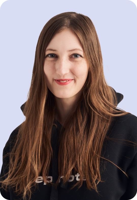 A person with long wavy brown hair and a black hoodie with the text 