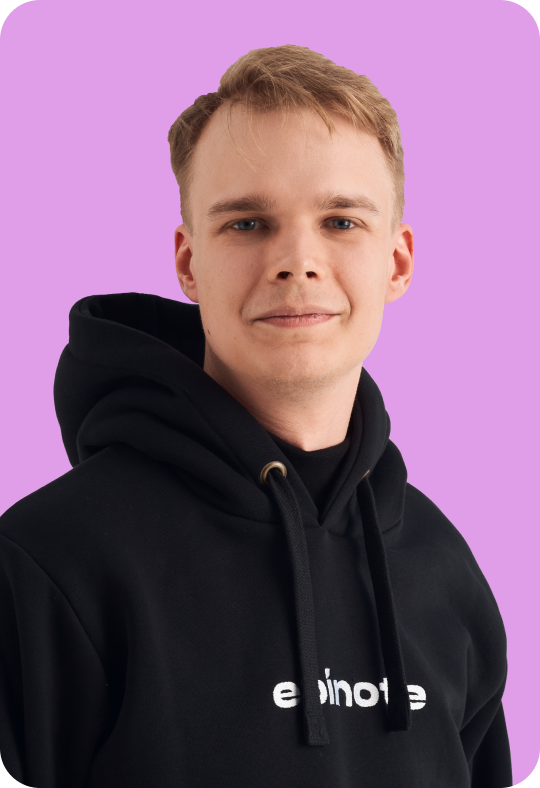 A person with short blond hair, wearing a black hoodie with the text 